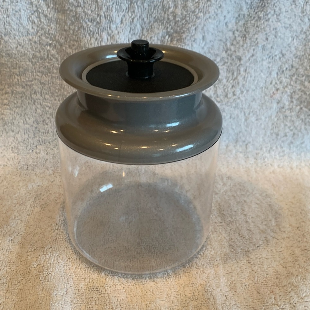 Tupperware NEW clear storage container with silver collar and black plunger lid.